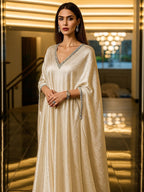Woman in a beige evening gown with intricate detailing going for eid
