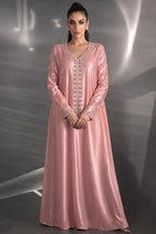 Woman wearing a pink evening gown with intricate detailing against a gray background