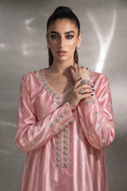 Woman wearing a pink traditional outfit with intricate designs against a neutral background