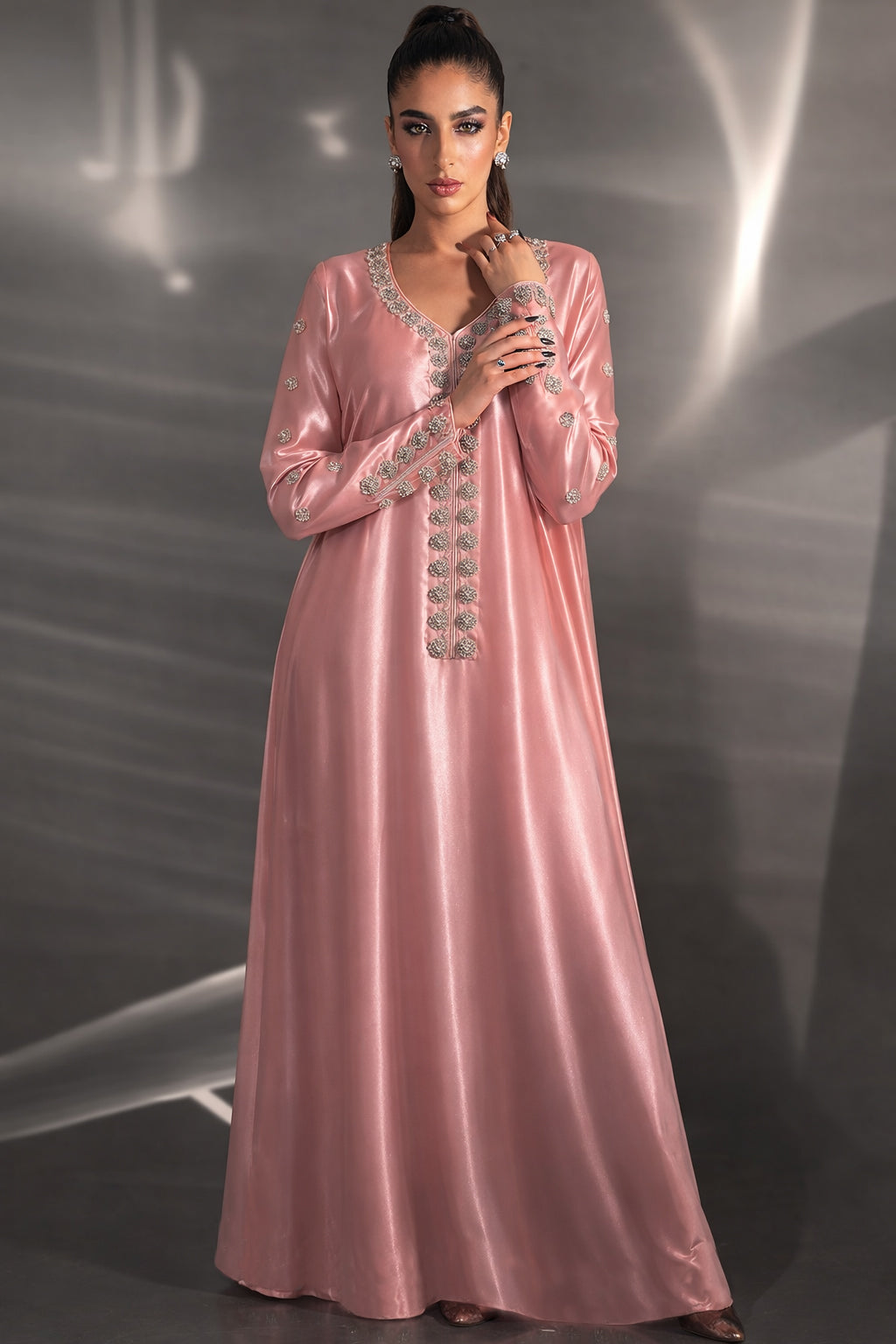Woman wearing a pink evening gown with intricate detailing against a dark background