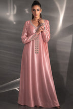 Woman wearing a pink evening gown with intricate detailing against a dark background