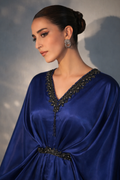 Woman wearing a blue dress with intricate detailing against a neutral background